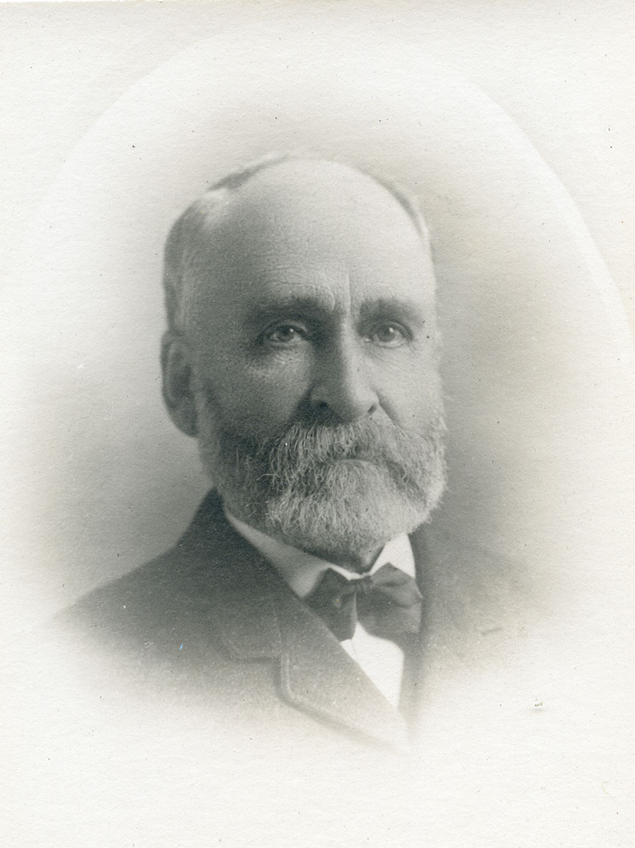 Historic image of an adult white male from the early 1900s wearing a formal jacket and shirt.