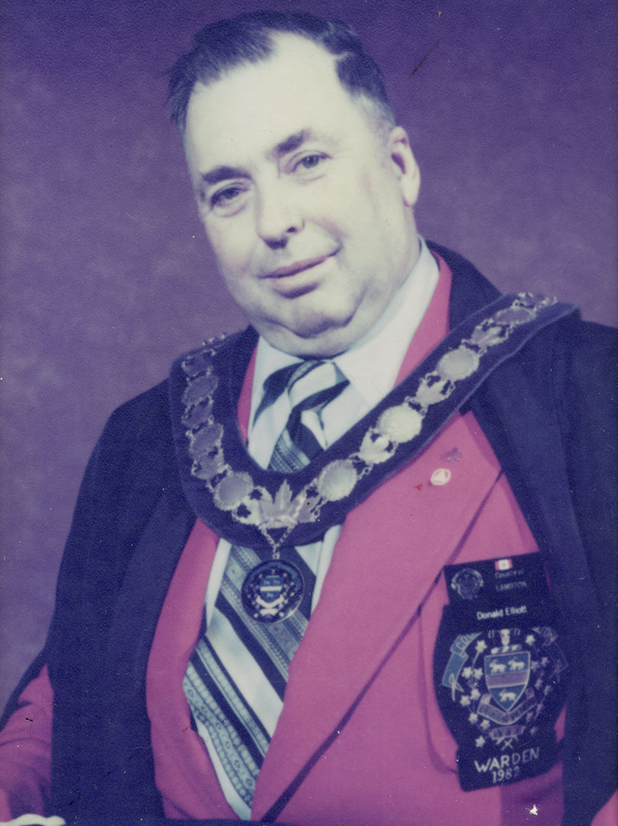 Photo of man in a suit and warden medal.