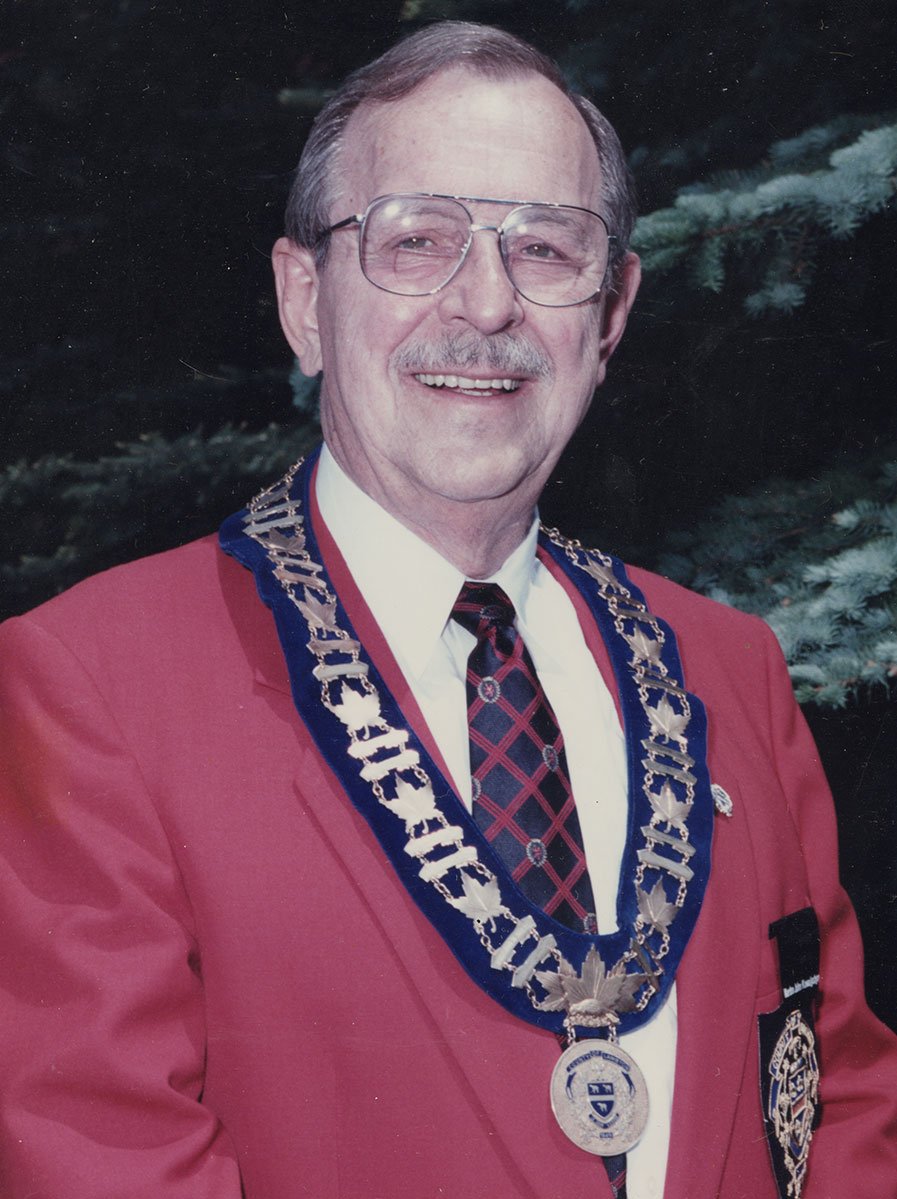 Photo of man in a suit and warden medal.