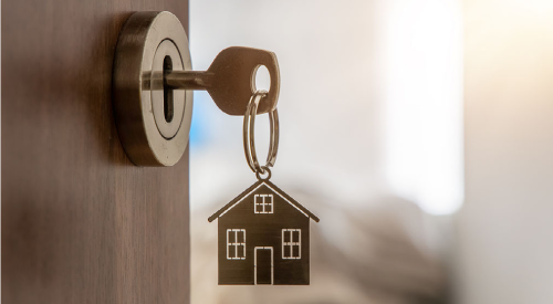 A key in the front door of a home, the door is open.