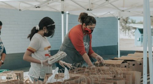 Two people preparing donation bags in an outdoor tent.