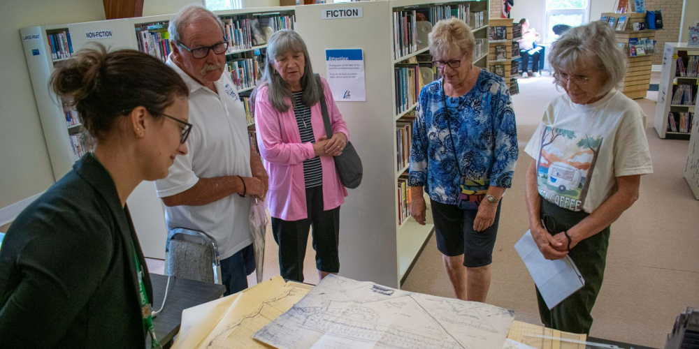 Archivist-Supervisor Nicole Aszalos examines a Bonnie Doone Subdivision Map from 1949 with members of the community at Show & Tell at Camlachie Library on Saturday, August 17