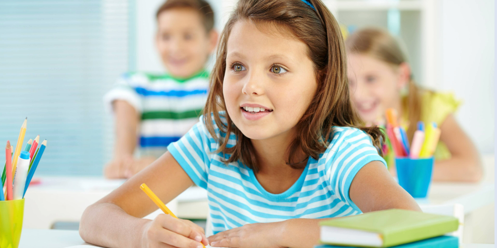 young girl sitting at a desk in a school class