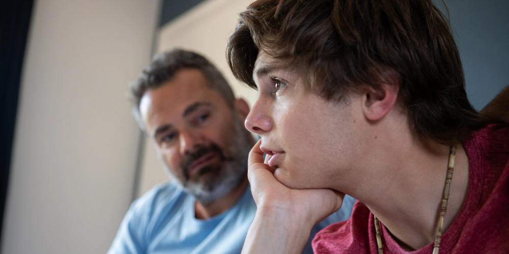 Young man sitting beside older man having a conversation